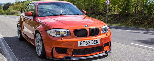 orange bmw driving on road orange bmw driving on road